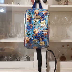 May include: A blue and white backpack with a Harry Potter theme. The backpack has a zipper closure and a black adjustable strap. The backpack features the Hogwarts house crests and the words "Slytherin", "Ravenclaw", "Hufflepuff", and "Gryffindor".