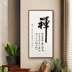 Può includere: Un'opera d'arte calligrafica in bianco e nero incorniciata con il carattere cinese "Zen" in grande scrittura. L'opera è su sfondo bianco ed è circondata da una cornice in legno. L'opera è appesa a una parete beige.