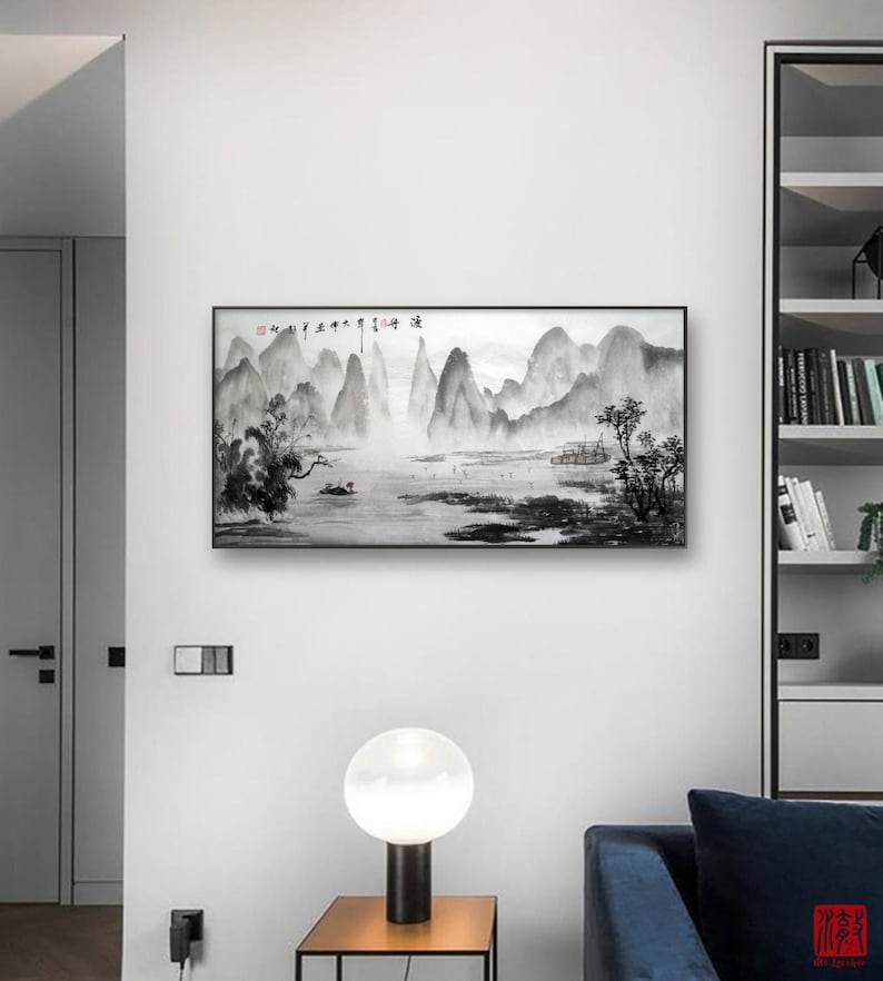 K&ouml;nnte beinhalten: Ein Schwarzwei&szlig;-Tuschbild einer Berglandschaft mit einem Fluss im Vordergrund. Das Bild ist in einem schwarzen Rahmen gerahmt und h&auml;ngt an einer wei&szlig;en Wand.