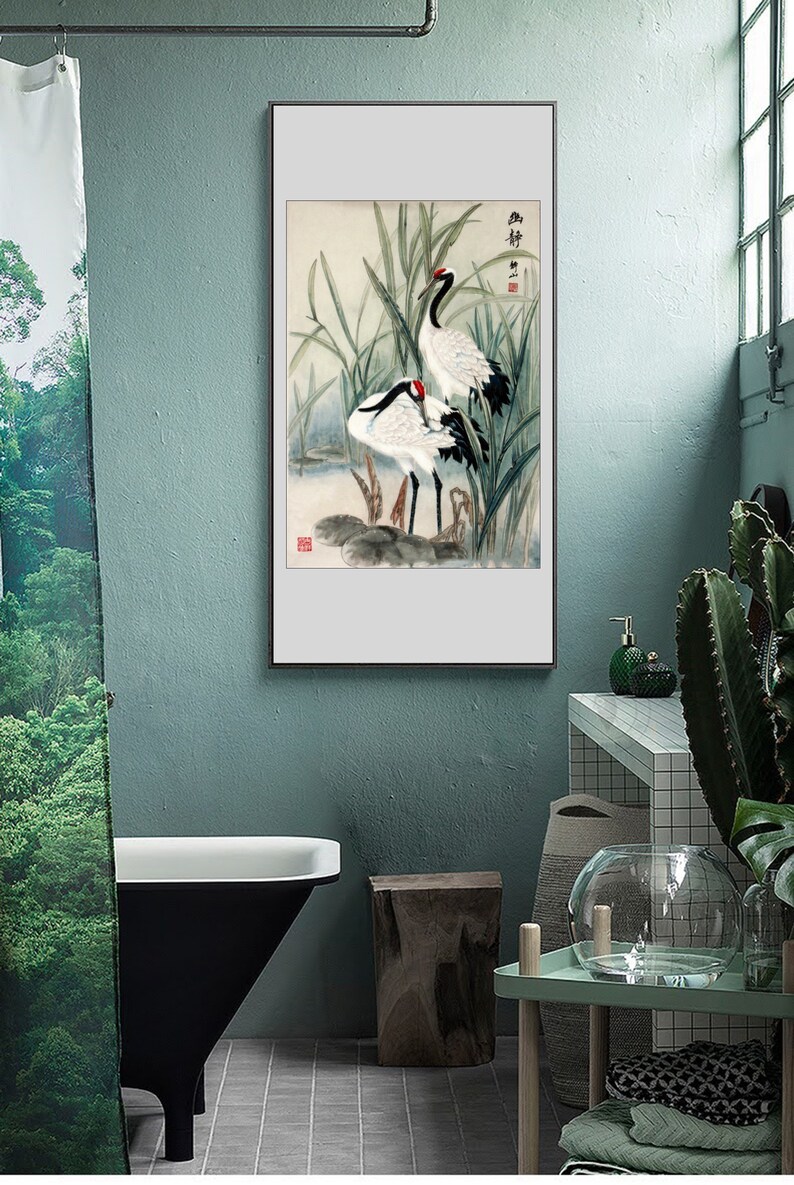 Puede incluir: Una pintura al agua enmarcada de dos grullas blancas de pie en un pantano con juncos verdes. La pintura tiene un fondo blanco y un marco negro.