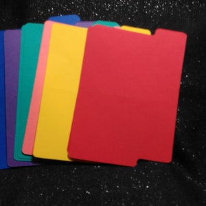 May include: A selection of brightly coloured file dividers in blue, purple, teal, pink, yellow, and red. Each divider has a tab and a rectangular shape, perfect for organising documents.