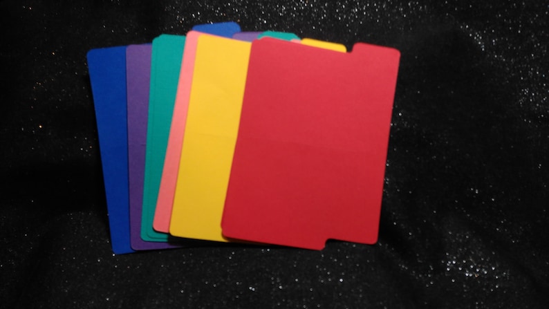 May include: A selection of brightly coloured file dividers in blue, purple, teal, pink, yellow, and red. Each divider has a tab and a rectangular shape, perfect for organising documents.
