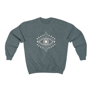 May include: A dark blue sweatshirt with a white graphic of a stylized eye with radiating lines and crescent moons.