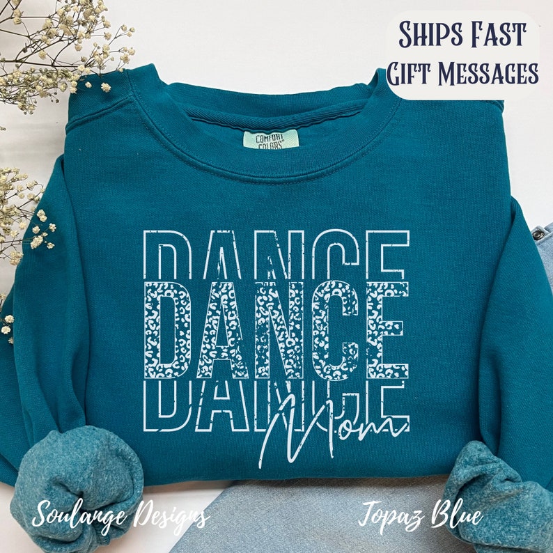 Peut inclure: Sweat-shirt bleu turquoise avec le texte "Dance Mom" en blanc avec un motif l&eacute;opard dans le mot "Dance".