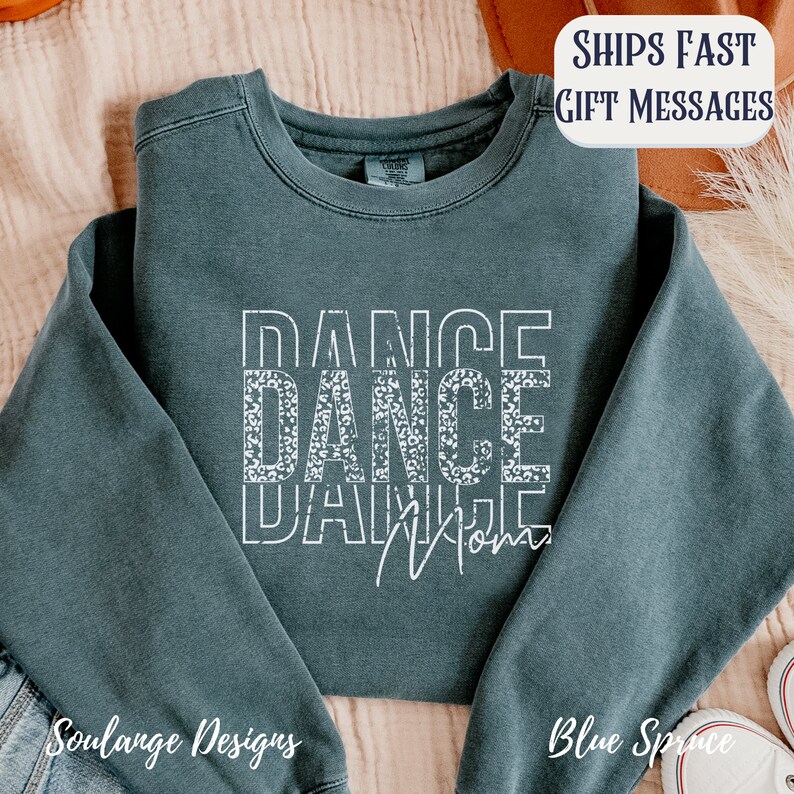 Peut inclure: Un sweat-shirt bleu sarcelle fonc&eacute; avec les mots "Dance Dance Mom" en blanc avec un motif l&eacute;opard sur le deuxi&egrave;me "Dance".