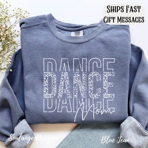 Peut inclure: Un sweat-shirt bleu avec les mots "Dance Dance Mom" en blanc avec un motif l&eacute;opard. Les mots sont empil&eacute;s verticalement.