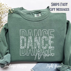 Peut inclure: Un sweat-shirt vert clair avec les mots "DANCE DANCE DANCE" en blanc avec un motif l&eacute;opard. Les mots sont empil&eacute;s les uns sur les autres. Le sweat-shirt a un col rond et des manches longues.