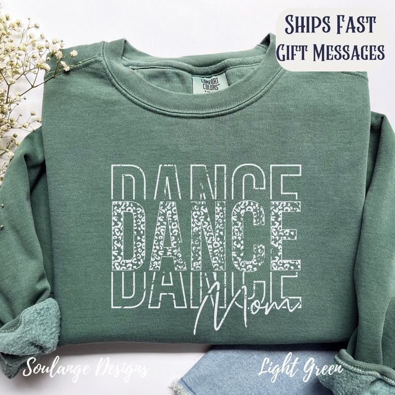 Peut inclure: Un sweat-shirt vert clair avec les mots "DANCE DANCE DANCE" en blanc avec un motif l&eacute;opard. Les mots sont empil&eacute;s les uns sur les autres. Le sweat-shirt a un col rond et des manches longues.