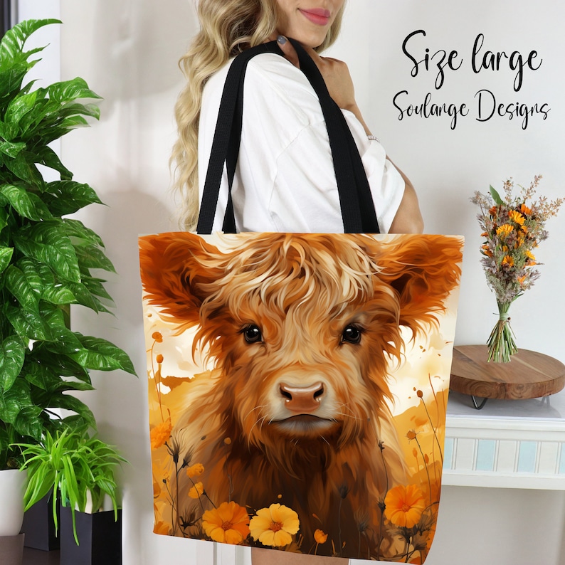 May include: A large tote bag featuring a close-up of a Highland cow with a soft, fuzzy brown coat. The cow is looking directly at the viewer with big, brown eyes. The background is a watercolor-style painting of yellow flowers.