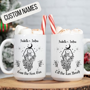 K&ouml;nnte beinhalten: Zwei wei&szlig;e Keramikbecher mit schwarzen Designs. Die Becher zeigen ein Skelettpaar, das sich in den Armen h&auml;lt, mit dem Text "Isabella & Joshua" und "From Our First Kiss" auf einem Becher und "Isabella & Joshua" und "Till Our Last Breath" auf dem anderen.