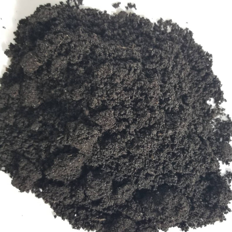 May include: A close-up of a pile of dark brown, crumbly soil. The soil is rich and fertile, perfect for planting seeds or growing plants.
