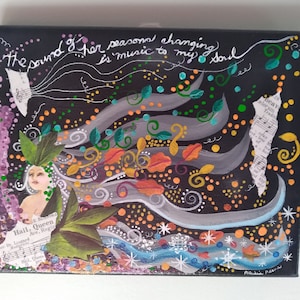 May include: A black canvas painting with a whimsical design featuring a woman with flowing hair, leaves, and musical notes. The text "The sound of her seasons changing is music to my soul" is written in cursive across the top of the painting.