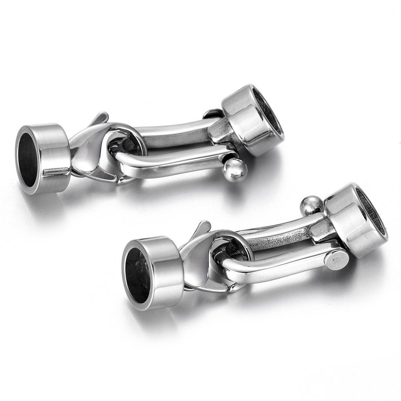 May include: Two silver-toned metal clasps with a round, cylindrical end piece. The clasps are designed to be used for jewelry making or other crafting projects.