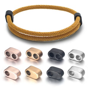 Op de afbeelding: Set van acht metalen koord eindkappen in verschillende afwerkingen, waaronder roségoud, goud, zwart en zilver. De eindkappen hebben twee gaten om koord door te rijgen.