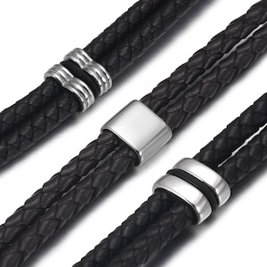 May include: Two black leather bracelets with silver metal accents. The bracelets are braided and have a simple design.