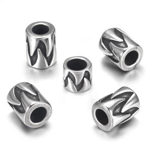 Puede incluir: Cinco cuentas de metal plateado con un diseño en zigzag. Las cuentas son cilíndricas con un agujero en el centro. Las cuentas están dispuestas sobre una superficie blanca. Estas cuentas son adecuadas para la fabricación de joyas.