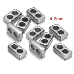May include: A group of ten silver-toned metal bead spacers with two holes each. The spacers are rectangular in shape and measure 4.2 mm in length.