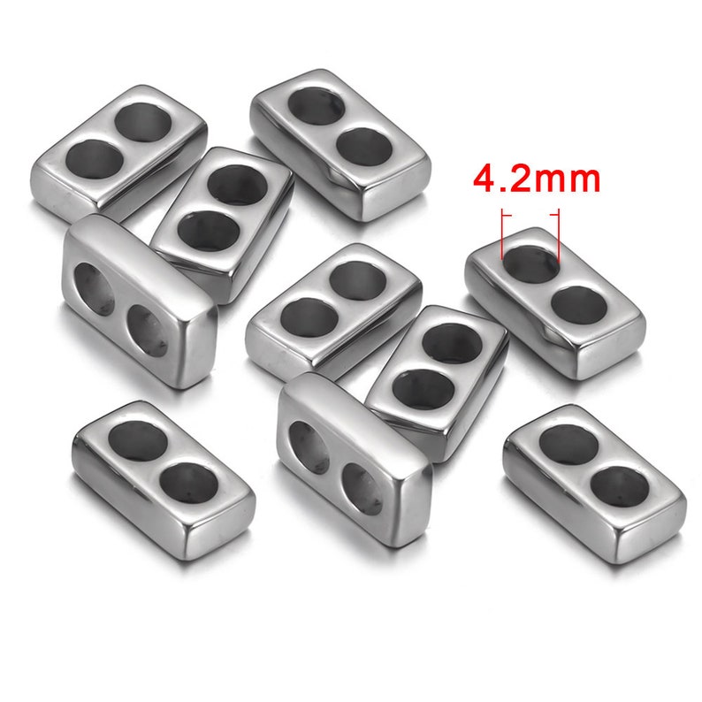 May include: A group of ten silver-toned metal bead spacers with two holes each. The spacers are rectangular in shape and measure 4.2 mm in length.