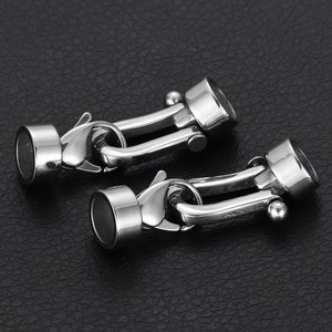 May include: Two silver metal clasps with a hook and loop closure. The clasps are designed to connect two pieces of jewelry or other items.