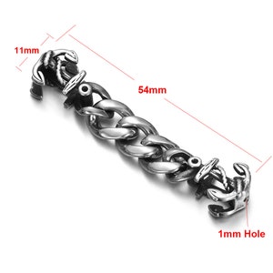 May include: Silver-toned stainless steel bracelet with two anchor-shaped clasps. The bracelet is 5.4 cm long and 1.1 cm wide. The clasp has a 1 mm hole.