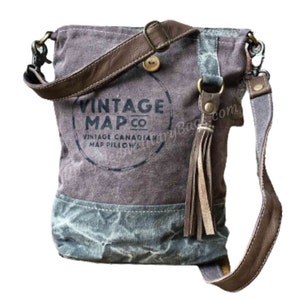 May include: A brown canvas crossbody bag with a leather strap and a tassel. The bag has a circular logo that says "Vintage Map Co. Vintage Canadian Map Pillows".
