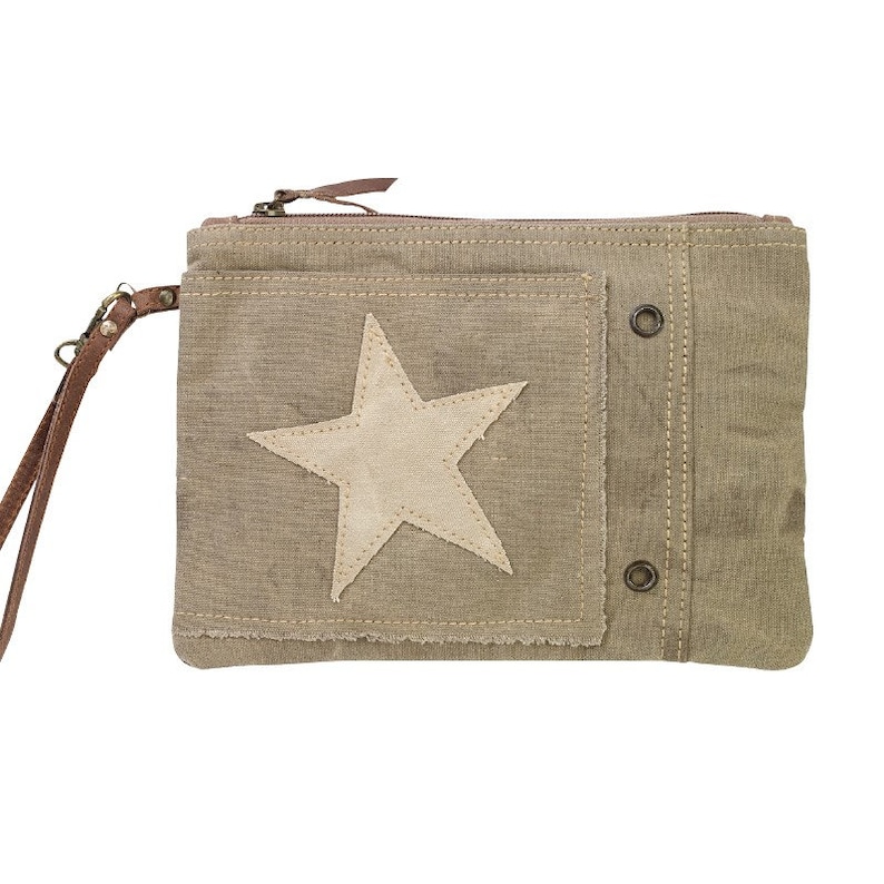 May include: A beige canvas clutch with a zipper closure and a brown leather strap. The clutch has a large white star patch on the front and two metal snaps on the side.