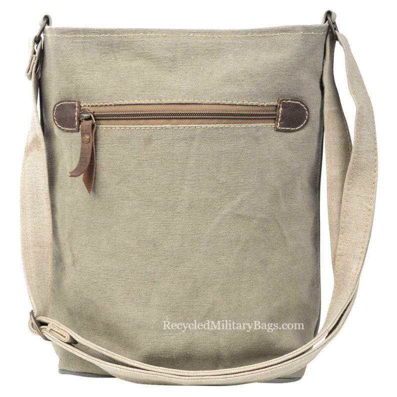 May include: A light green canvas crossbody bag with a zippered pocket and a brown leather strap. The bag has a white strap and the text "RecycledMilitaryBags.com" is printed on the bottom.