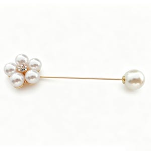 May include: A gold-toned lapel pin featuring a flower-shaped cluster of five white faux pearls with a small clear rhinestone at the center. The pin has a long, thin gold-toned metal stem that ends with a single, larger white faux pearl at the tip.