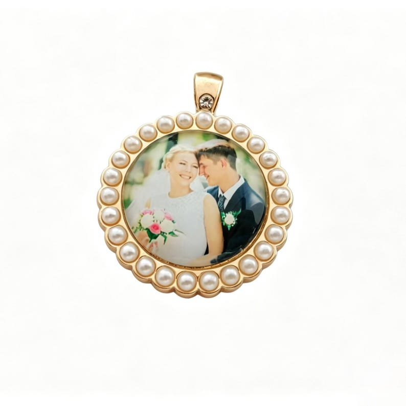 May include: A round gold-toned pendant featuring a central photograph of a bride and groom. The circular frame is bordered by a series of small white pearls and includes a small clear crystal accent at the top bail for a necklace attachment.