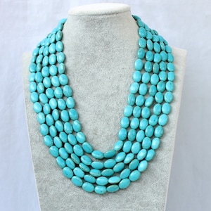 May include: A turquoise multi-strand necklace made of oval-shaped beads. The necklace is layered and has a long length.