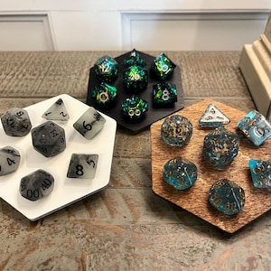 May include: Three hexagonal trays with different colored dice. The first tray is white with black and white dice. The second tray is black with green and gold dice. The third tray is brown with blue and gold dice.