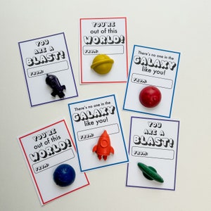 May include: Cards with space-themed messages and small toy space objects. The cards have phrases like "You are a Blast!" and "You're out of this world!" with a space for "From:". Includes a toy spaceship, planet, and rocket.