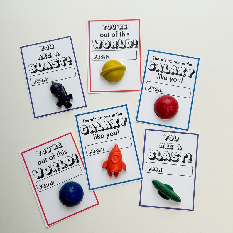 May include: Cards with space-themed messages and small toy space objects. The cards have phrases like "You are a Blast!" and "You're out of this world!" with a space for "From:". Includes a toy spaceship, planet, and rocket.