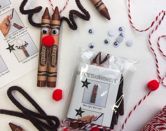 May include: A craft kit for making reindeer ornaments. The kit includes brown crayons, googly eyes, red pom-poms, brown pipe cleaners, and a small instruction booklet. The Crayola crayons are the main body of the reindeer.