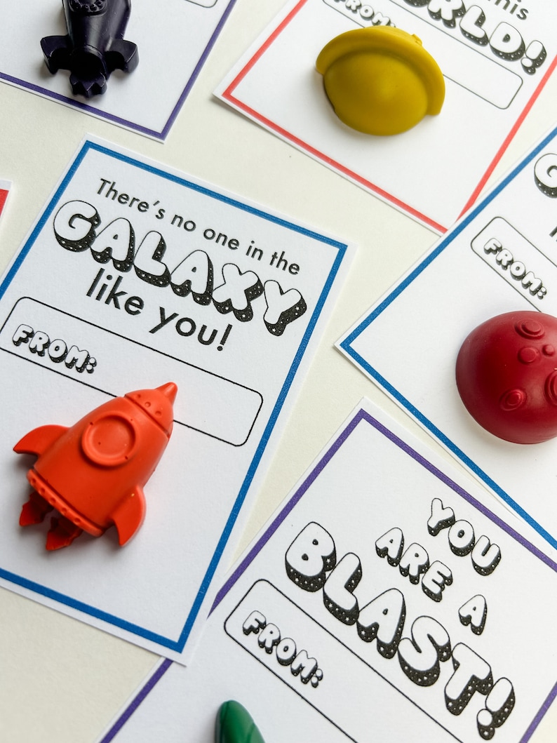 May include: Cards with space-themed designs and accompanying small, colorful plastic shapes. The cards have phrases like "There's no one in the GALAXY like you!" and "YOU ARE A BLAST!" with space-themed shapes like rockets and planets.