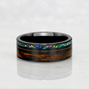 May include: A black ceramic ring with a band of brown wood and a thin line of iridescent opal.