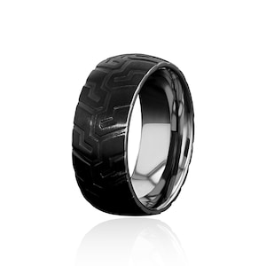 以下が含まれることがあります： タイヤのトレッドパターンがデザインされた、黒と銀の結婚指輪です。