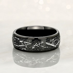 May include: A black ring with a silver-toned, distressed finish. The ring has a wide band and a smooth, polished interior.