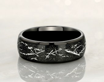 May include: A black ring with a silver-toned, distressed finish. The ring has a wide band and a smooth, polished interior.