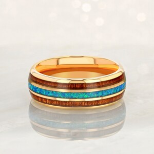 May include: A gold band with a wood inlay and blue opal accents. The ring is a classic design with a modern twist.