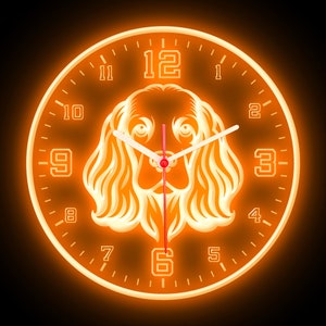 May include: Orange glow clock with a dog silhouette in the center. The clock face has black numbers and hands. The dog is facing forward with its head tilted slightly down.