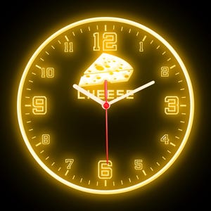 Può includere: Un orologio al neon giallo con indicatori delle ore in numeri romani neri e indicatori dei minuti in numeri arabi neri. Il quadrante dell'orologio ha un pezzo di formaggio con la parola "CHEESE" stampata sotto.