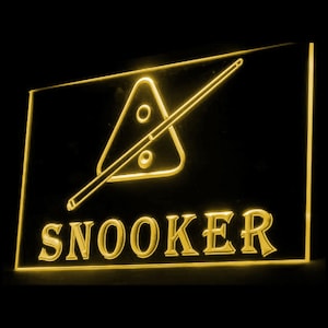 Può includere: Un cartello al neon giallo con un biliardo e un triangolo di biliardo, con la parola "SNOOKER" in grandi lettere.