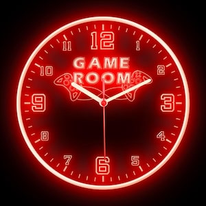 May include: A red neon clock with black numbers and a game controller design. The clock face reads "GAME ROOM".