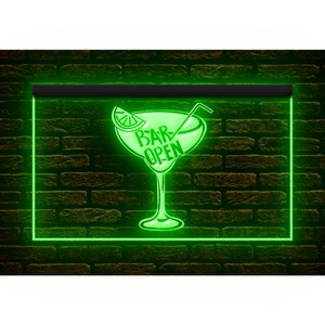 May include: A neon green sign featuring a margarita glass design with the text "BAR OPEN". The sign is framed in green and set against a brick wall. The margarita glass includes a lime wedge and a straw.