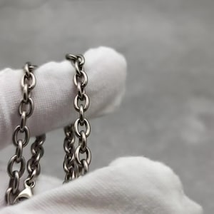 May include: A silver chain necklace with a delicate, linked design. The chain is displayed on a white surface.