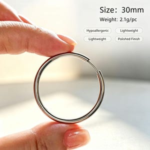 Könnte beinhalten: Ein silberfarbener Metall-Creolen-Ohrring mit polierter Oberfläche. Der Ohrring hat eine Größe von 30mm und ein Gewicht von 2,1g pro Stück. Der Text auf dem Bild lautet Size: 30mm, Weight: 2.1g/pc, Hypoallergenic, Lightweight und Polished Finish.