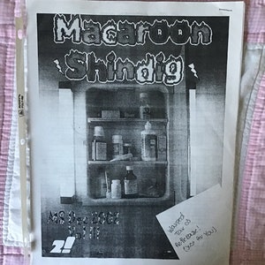 Op de afbeelding: Een zwart-wit print getiteld "Macaroon Shindig" met een illustratie van een medicijnkast. De tekst "MS Dec 2002 Vol III" is ook zichtbaar. Een handgeschreven notitie luidt "Warped Tar 03 Re-feBase! (Just for You)". De print zit in een transparante plastic hoes.