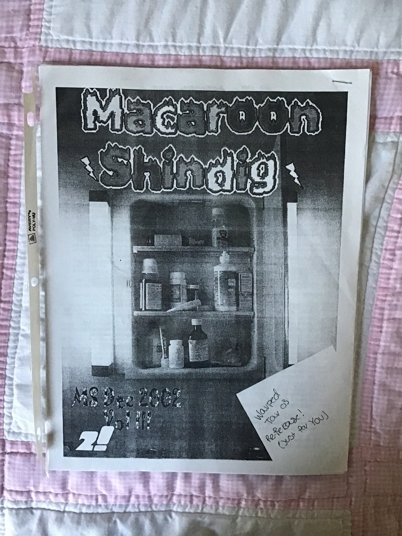 Op de afbeelding: Een zwart-wit print getiteld "Macaroon Shindig" met een illustratie van een medicijnkast. De tekst "MS Dec 2002 Vol III" is ook zichtbaar. Een handgeschreven notitie luidt "Warped Tar 03 Re-feBase! (Just for You)". De print zit in een transparante plastic hoes.