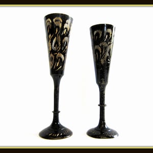 May include: Two black and gold decorative vases with a floral design. The vases are tall and slender with a flared top and a round base.